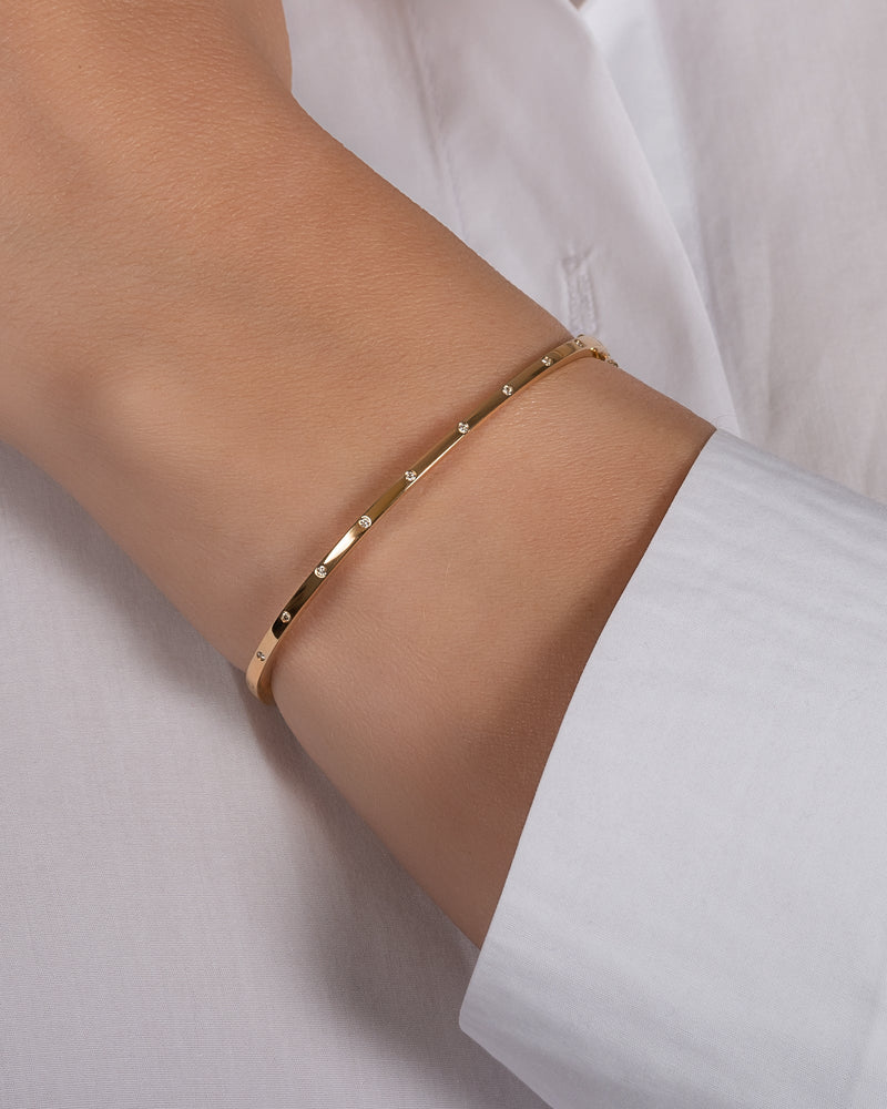 Gold bracelet on a wrist with a white shirt background